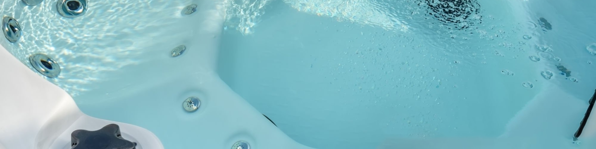 Image d'un jacuzzi en fonctionnement sur un balcon, où on peut voir en arrière-plan à gauche des chaises en bois.